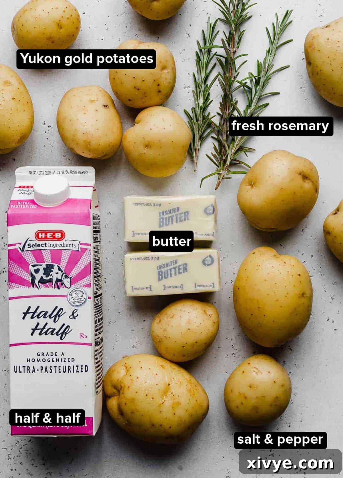 Rosemary Brown Butter Mashed Potatoes ingredients laid out on a light gray background: Yukon gold potatoes, half and half, fresh rosemary sprigs, unsalted butter, and a pinch of salt and pepper.