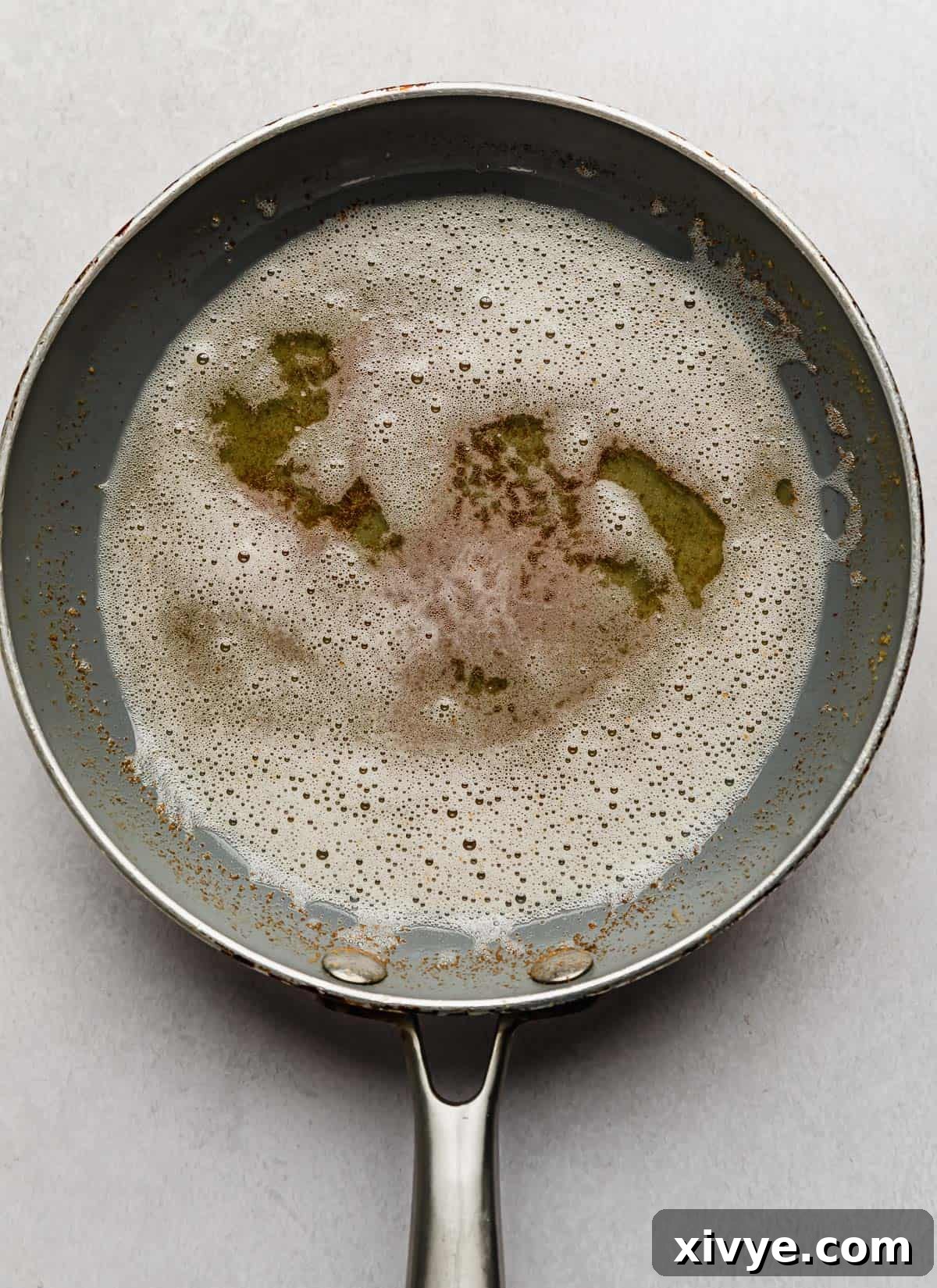 Close-up of golden brown butter simmering in a small grey skillet, showcasing the toasted milk solids.
