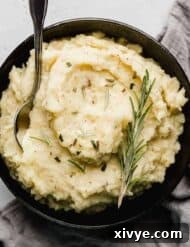 Rosemary Brown Butter Mashed Potatoes in a black bowl on a light gray background.