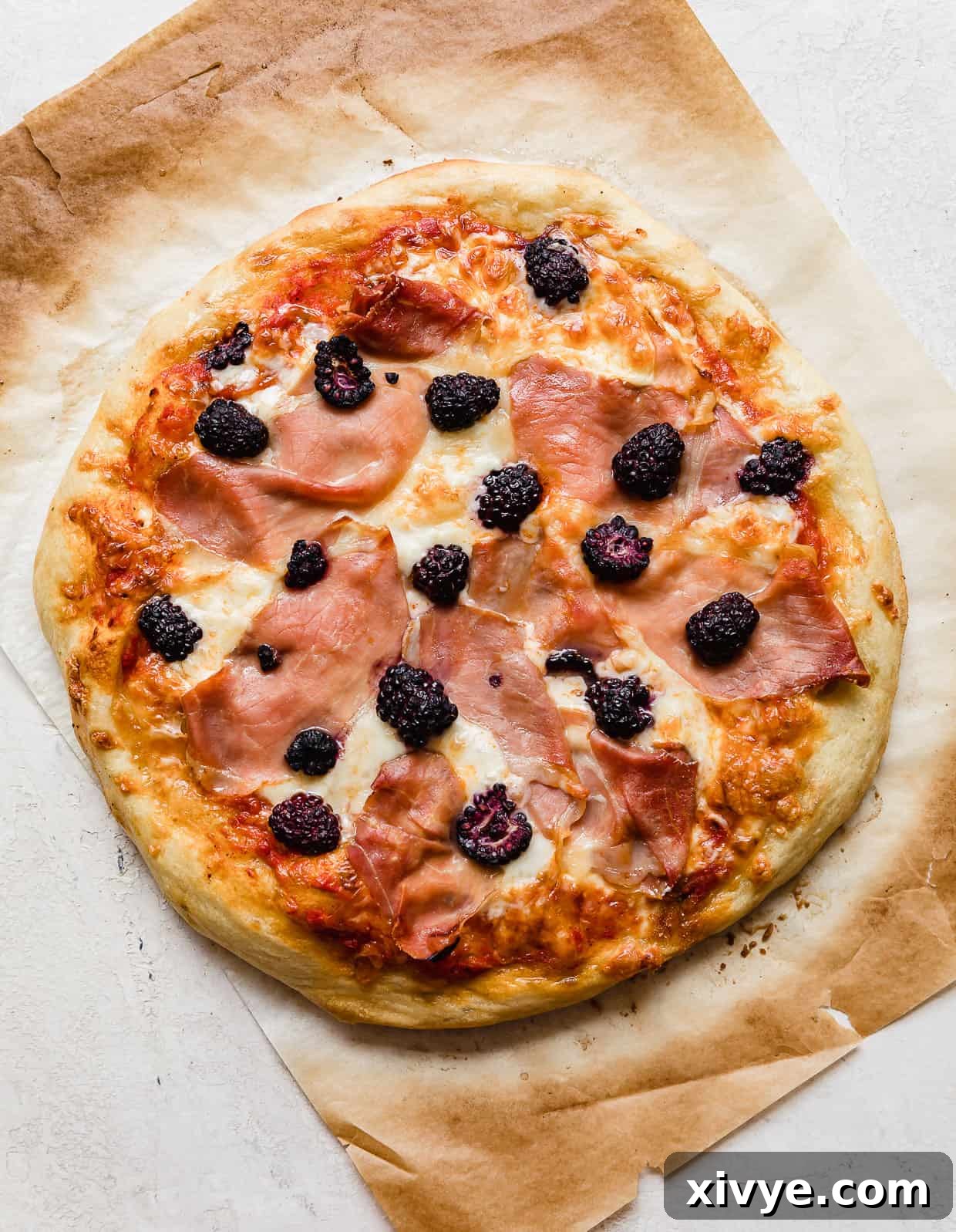 A freshly baked blackberries pizza, garnished with fresh basil, showcasing its golden crust and melted cheese.