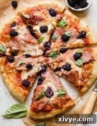 Blackberry Pizza topped with fresh basil and blackberries, sliced into 6 pieces.