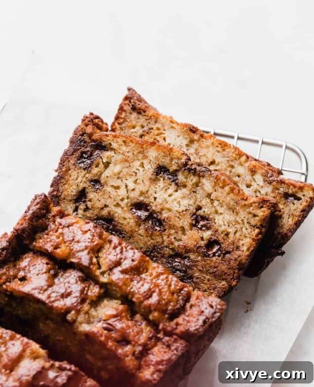 Slices of incredibly moist Chocolate Chip Banana Bread, showcasing melted chocolate chips and a tender crumb, arranged against a clean white background.