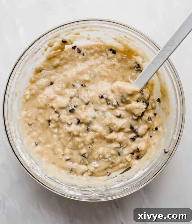 Chocolate Chip Banana Bread batter in a glass bowl against a white background.