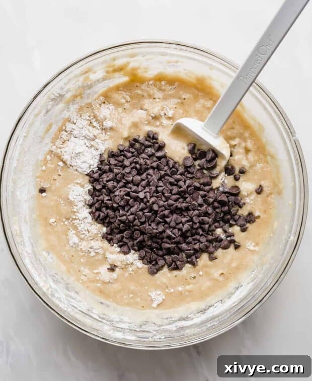 Chocolate chips with banana bread batter, in a glass bowl.