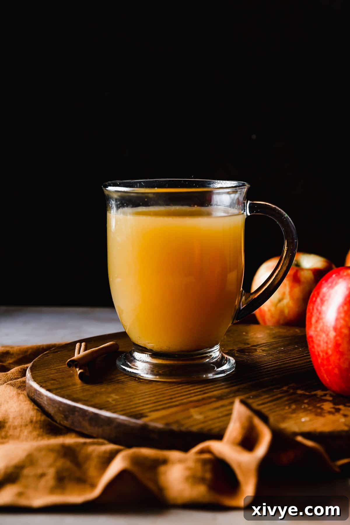 A clear mug filled with Hot Wassail against a black background.