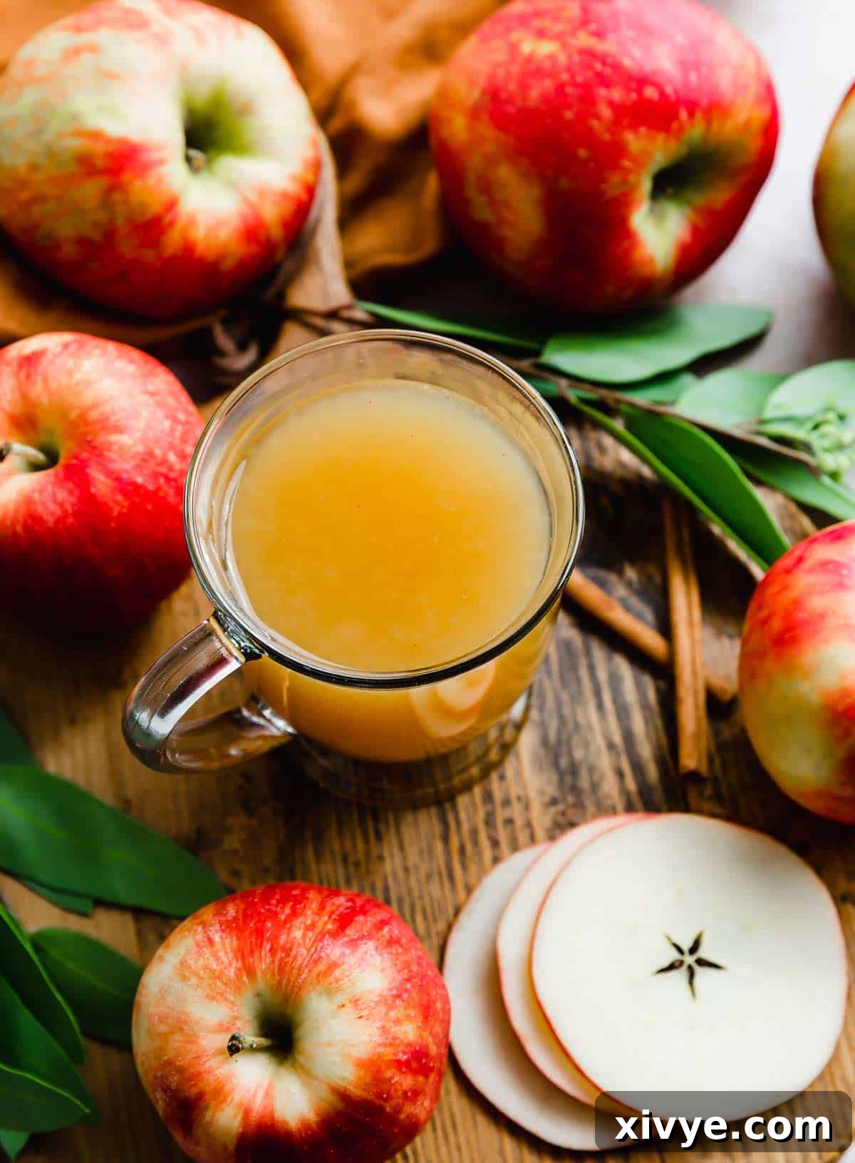 Overhead photo of Hot Wassail in a clear mug with apples surrounding the mug.