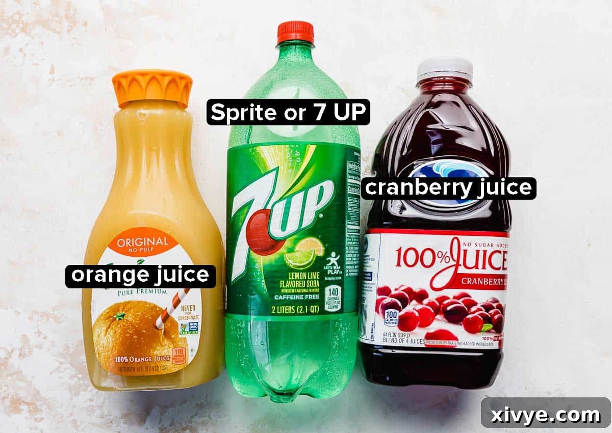 A visually appealing flat lay showcases the three essential ingredients for Christmas Slush punch: a clear bottle of Sprite, a carton of vibrant orange juice, and a bottle of rich cranberry juice, all arranged artfully on a clean white background.