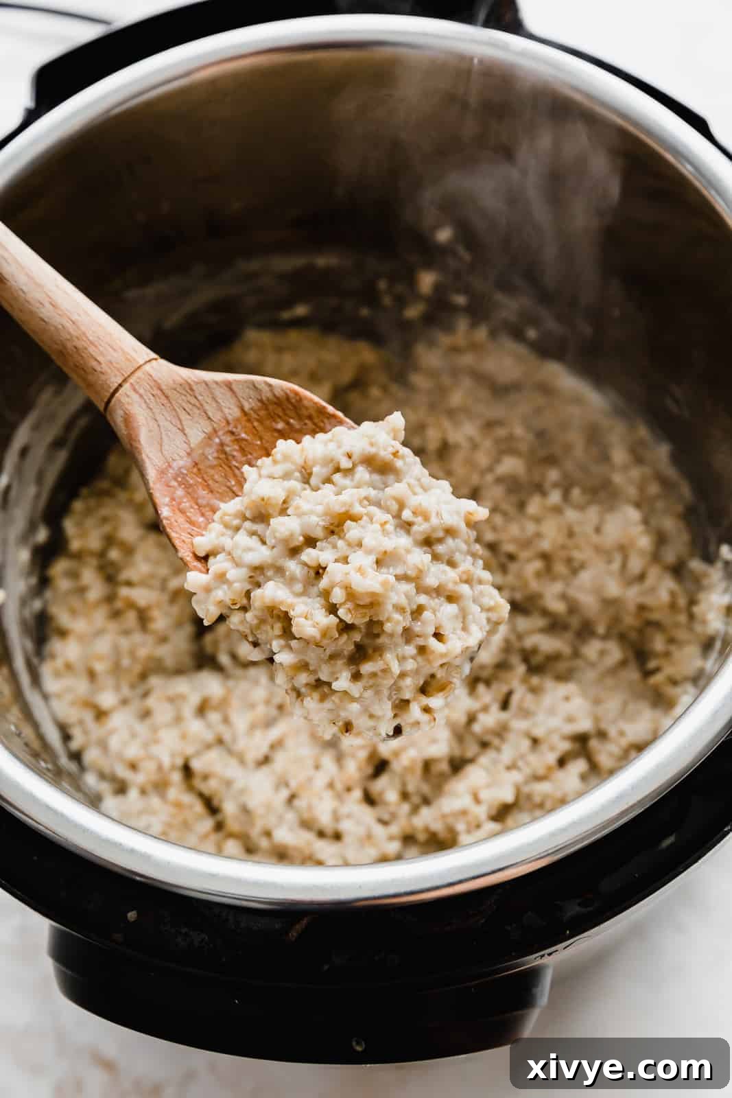 The Perfect Steel Cut Oats 7 A wooden spoon holding up a scoop of creamy steel cut oats.
