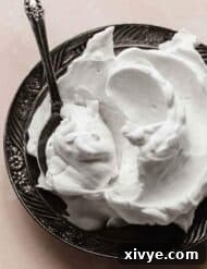 Coconut Whipped Cream on a black plate with a spoon scooped into the cream.