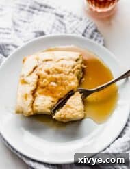 A square slice of German pancake on a white plate topped with syrup.