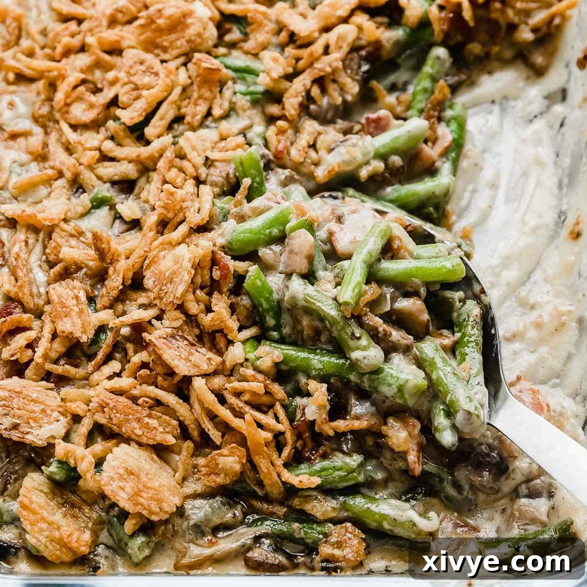A serving spoon scooping out French fried onion topped Bacon Green Bean Casserole.