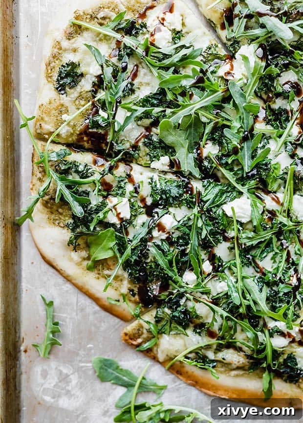 A tantalizing close-up of a Gourmet Crispy Kale Pizza, adorned with vibrant fresh arugula and crumbled goat cheese, elegantly drizzled with a rich balsamic glaze.