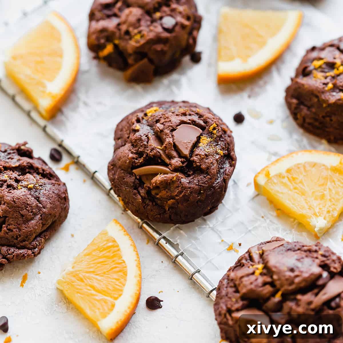 Festive Cookie Favorites Collection 4 Chocolate Orange Cookies on a wire rack surrounded by fresh orange slices.