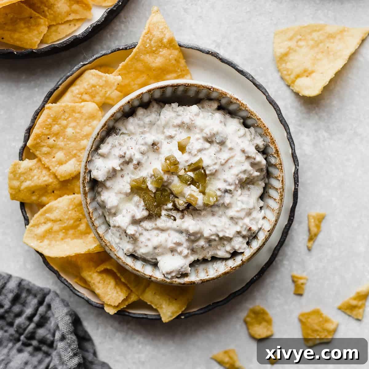 Cream Cheese Sausage Dip in a white bowl topped with chopped jalapeños.