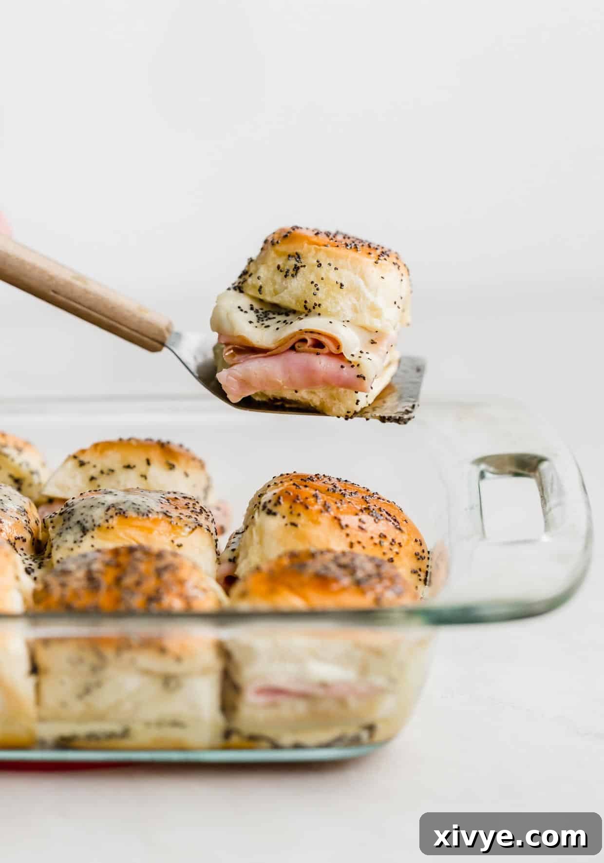 A single Honey Mustard Ham and Cheese Slider on a metal spatula against a white background.