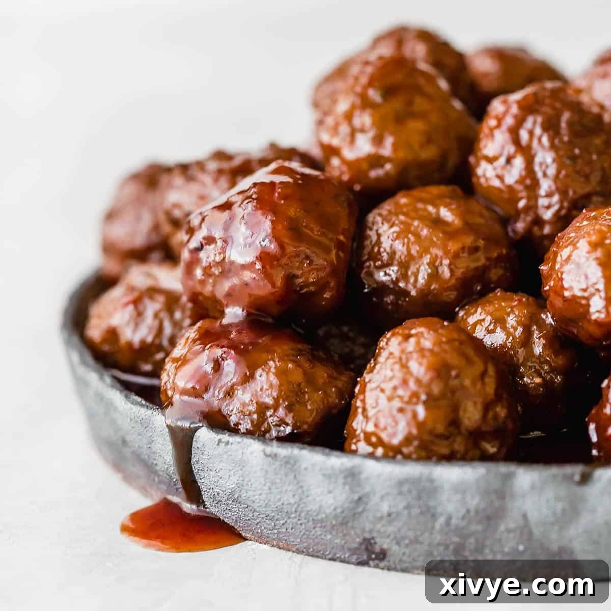 Crock pot Grape Jelly Meatballs on a black plate against a white background.
