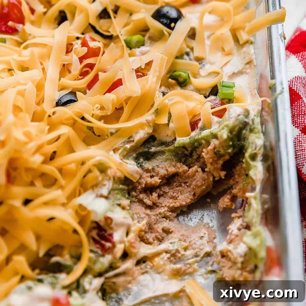 A 7 layer taco dip recipe in a glass pan.