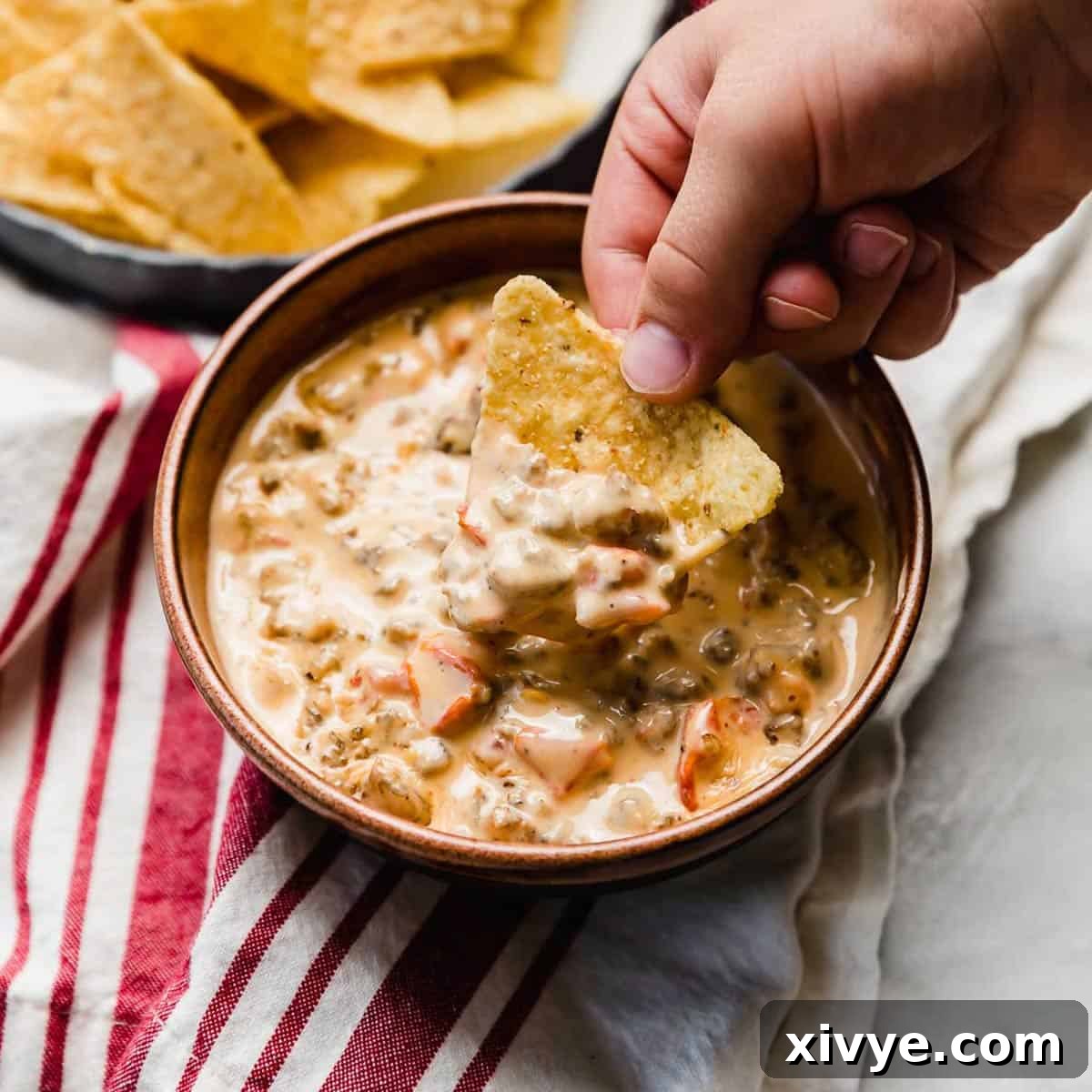 Cream Cheese Rotel and Sausage Dip in a brown bowl.