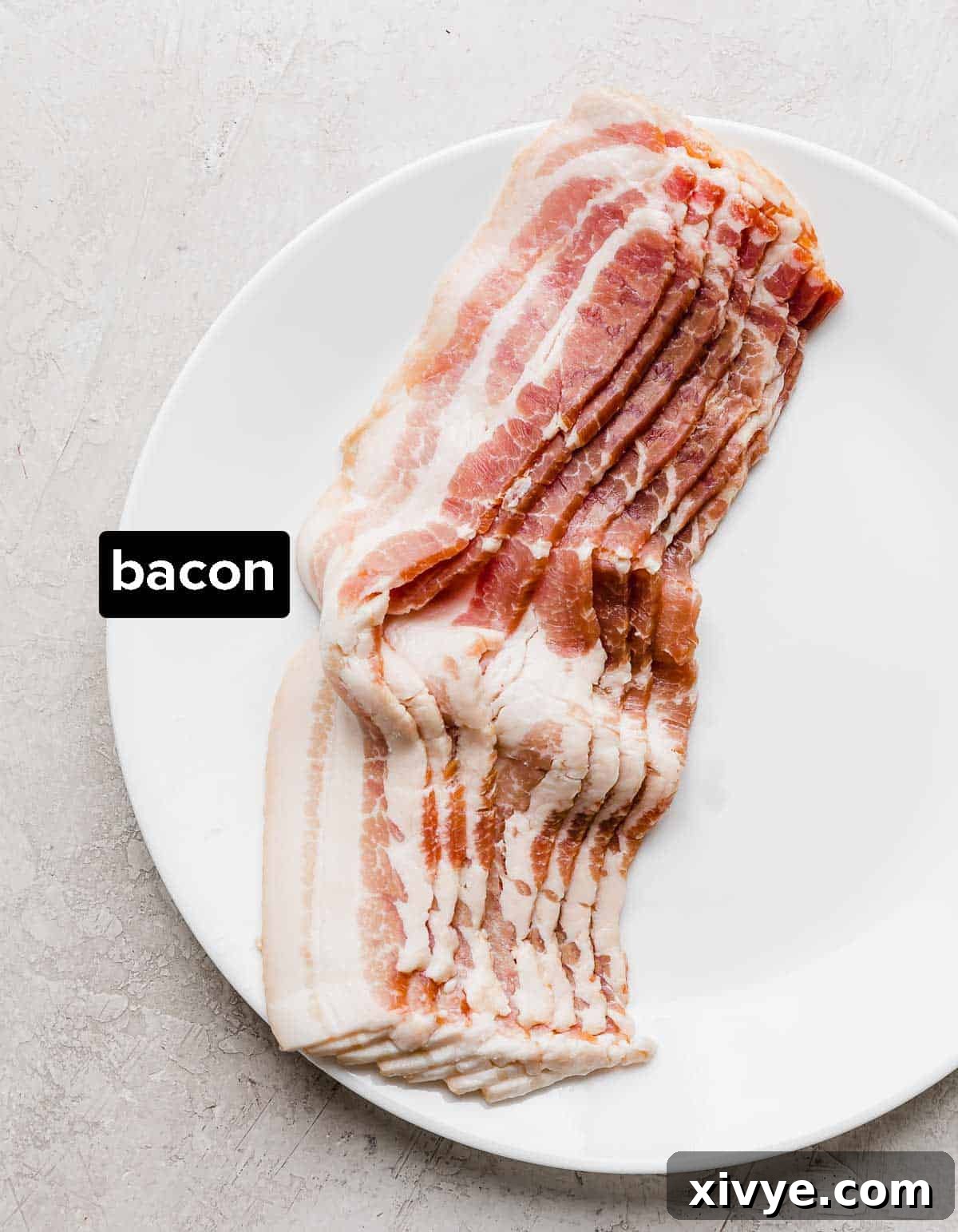 The Secret to Perfectly Crispy Oven Bacon 3 Raw, uncooked strips of bacon laid out neatly on a white plate, ready for preparation.