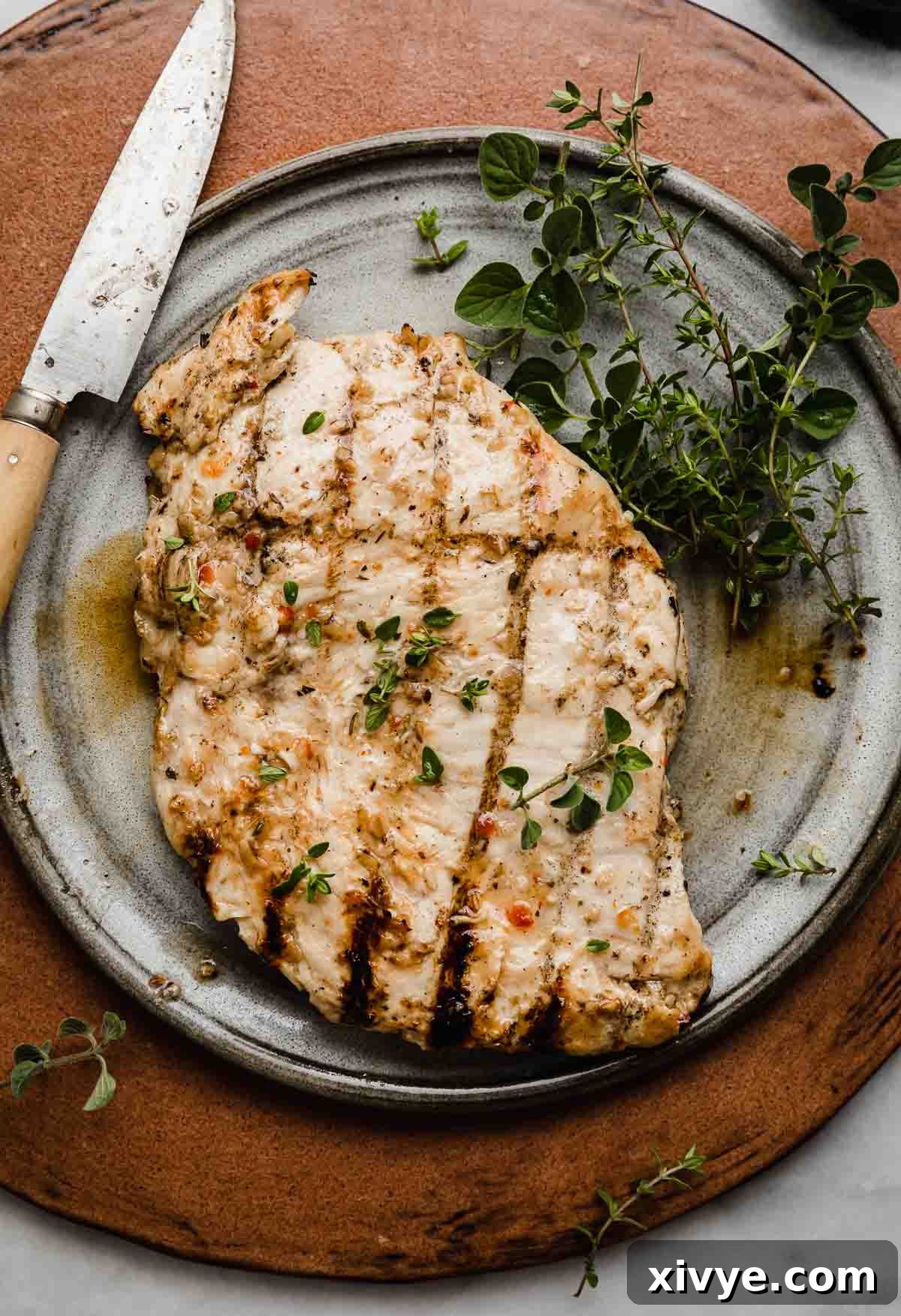 Tuscan Grilled Chicken 7 A grilled chicken that was marinated in an Italian chicken marinade, on a gray plate on a brown background.