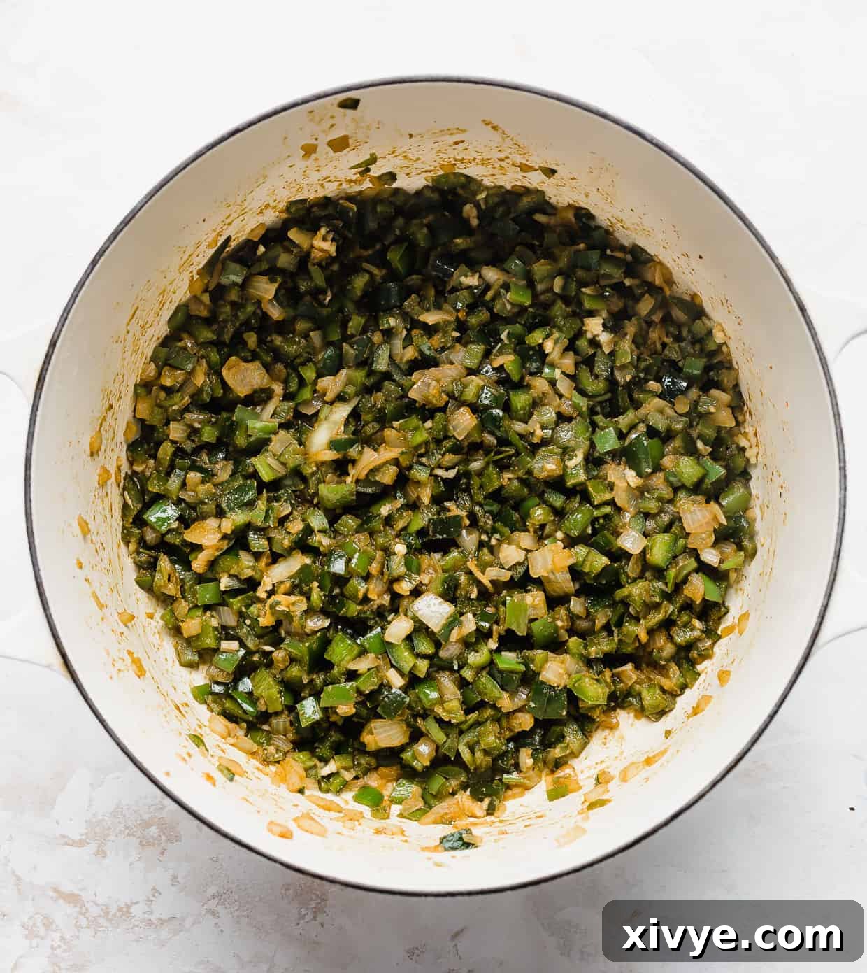 Creamy White Chicken Chili 5 A close-up shot of a large pot on a white background, filled with the savory mix of sautéed onions and green peppers, forming the robust start of the chili.