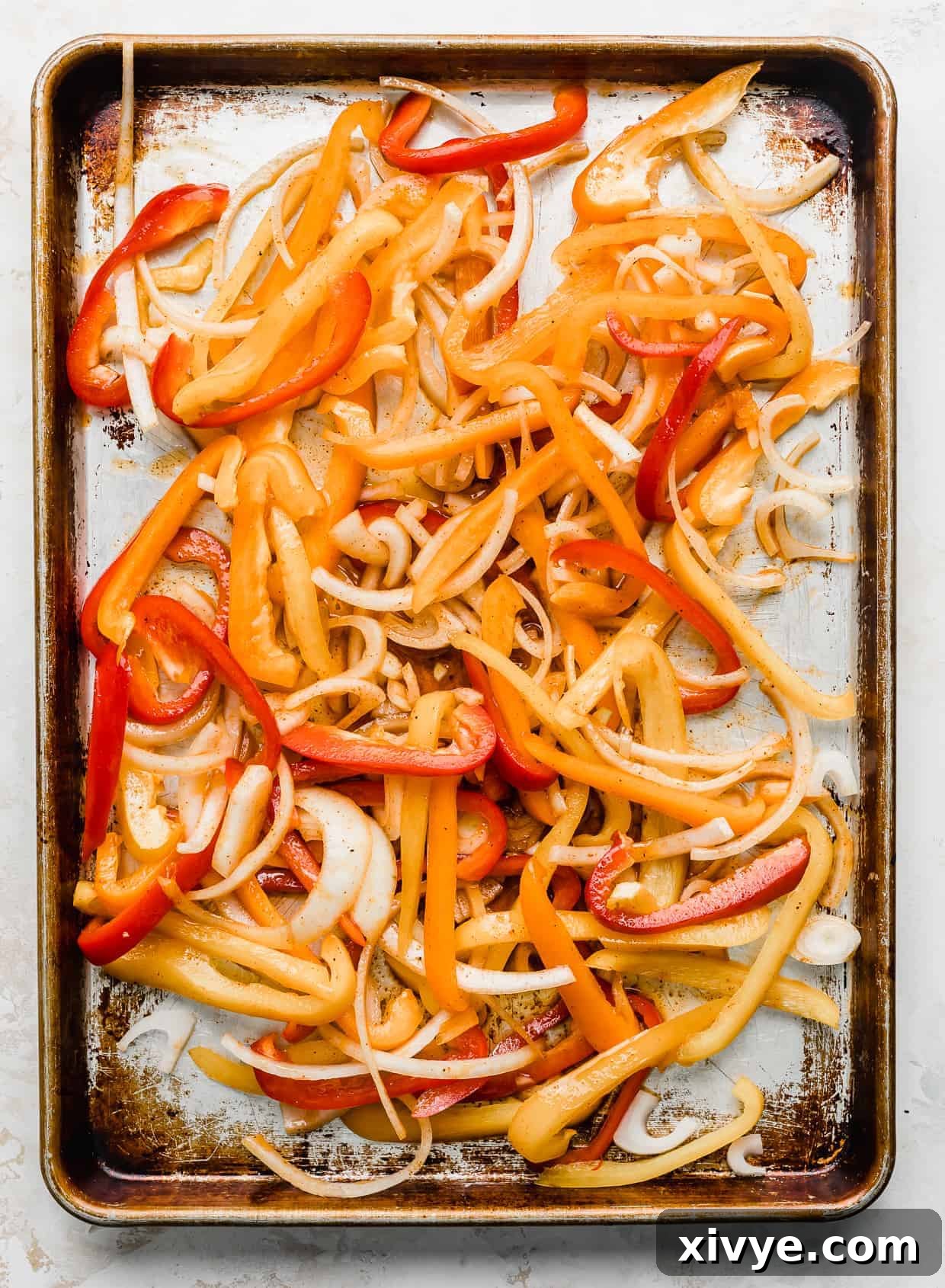 Sheet Pan Fiesta Shrimp 4 A baking sheet filled with vibrant, thinly sliced orange, red, and yellow bell peppers, ready for roasting in the oven, creating a colorful and inviting sight.