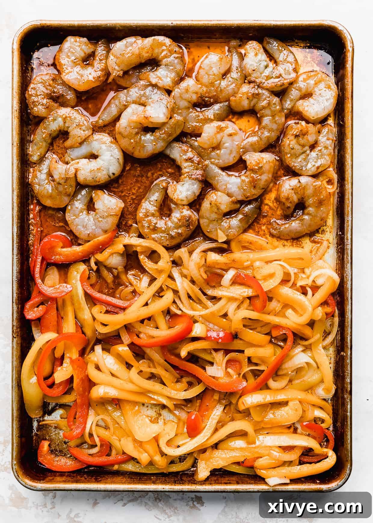 Sheet Pan Fiesta Shrimp 5 A close-up view of perfectly cooked shrimp and tender, colorful sliced bell peppers on a baking sheet, freshly removed from the oven and glistening with marinade.