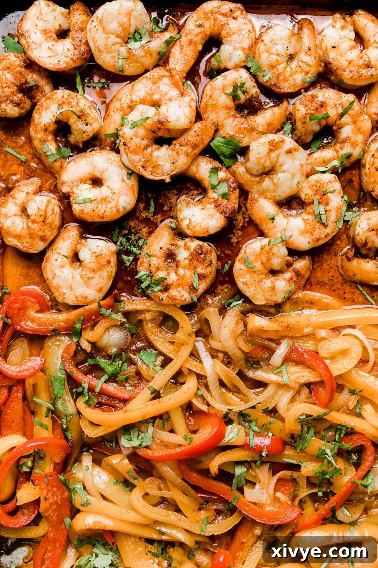 Sheet Pan Fiesta Shrimp 7 A close-up photograph of perfectly cooked shrimp alongside tender red, yellow, and orange bell peppers, showcasing the vibrant colors and appealing texture of the fajita filling.