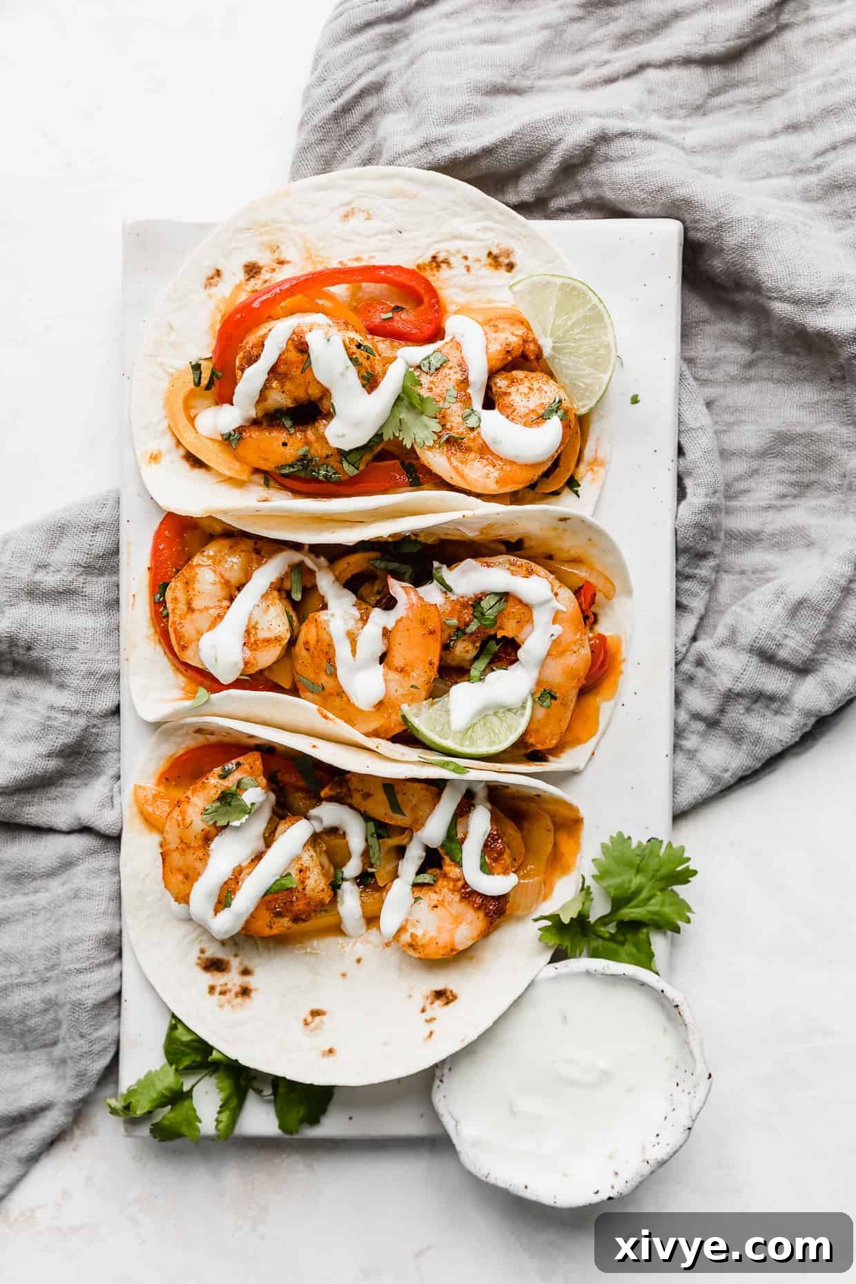 Sheet Pan Fiesta Shrimp 8 A vibrant and appealing shrimp fajita expertly placed on a white rectangular plate, resting elegantly on a stylish grey linen napkin, creating an inviting culinary presentation.